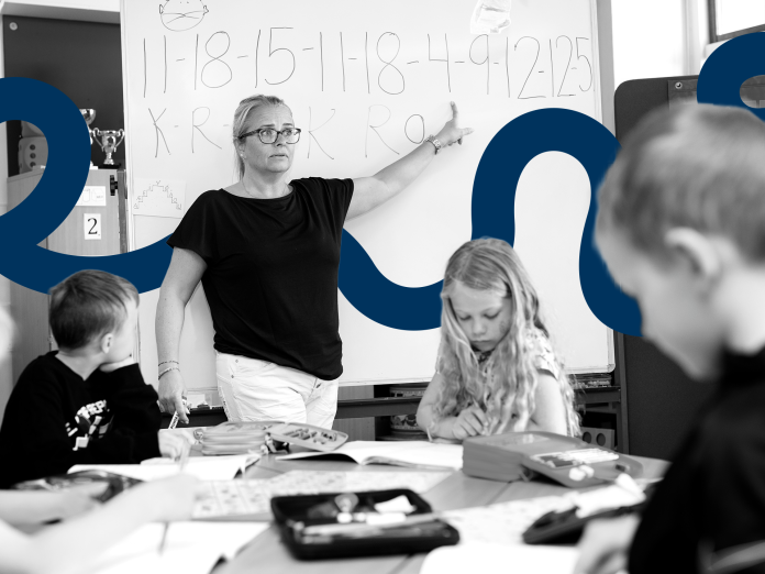 lærer foran tavle og tre elever sidder ved borde