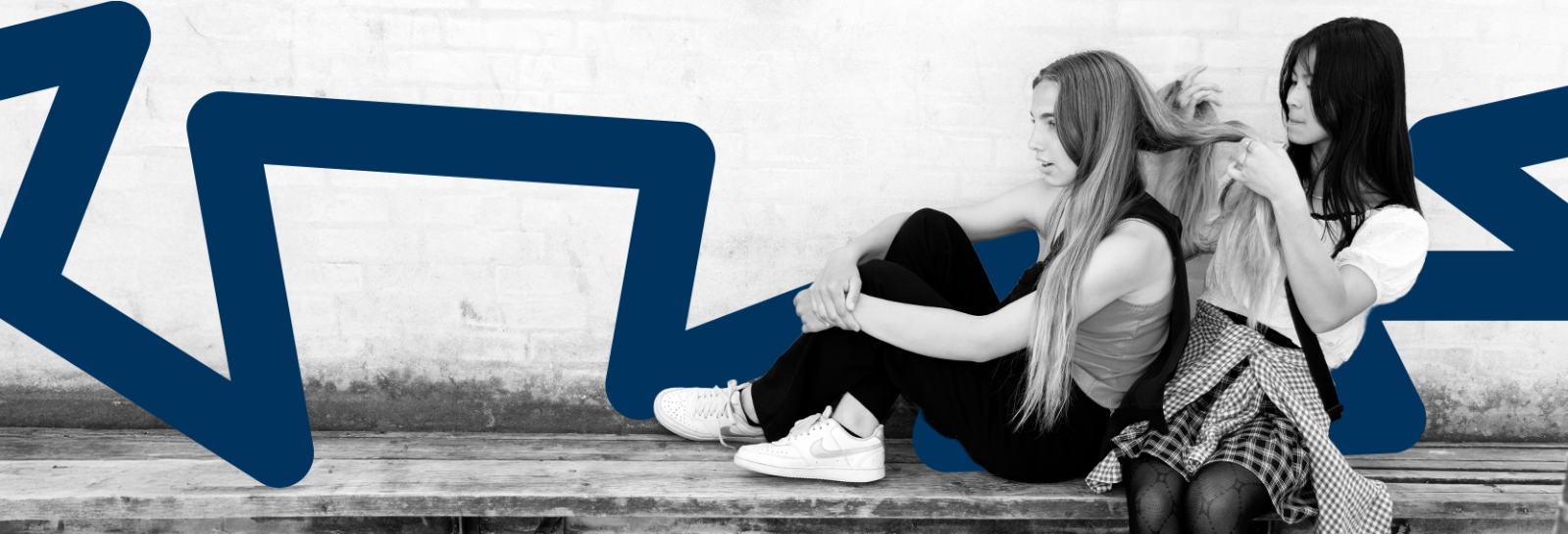 to piger på en bænk, den ene fletter den andens hår